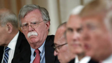 FILE PHOTO: Then-National Security Advisor John Bolton (L) listens as then-President Donald Trump (R) speaks during a meeting at his Mar-a-Lago resort in Palm Beach, Florida, April 18, 2018.