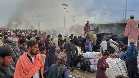 People gather beside a burnt truck after shelling by Afghan forces in Chaman, Pakistan, December 11, 2022