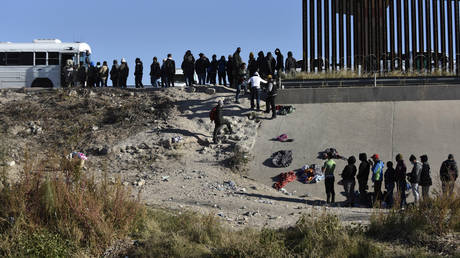 FILE PHOTO: Migrants wait to get on a US government bus after crossing the border from Ciudad Juarez, Mexico into El Paso, Texas, December 12, 2022.