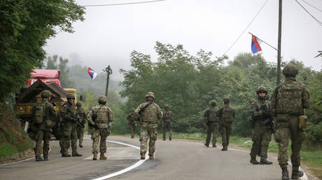 FILE PHOTO: Polish KFOR soldiers pass through barricades as they patrol near the Kosovo-Serbia border at Jarinje, October 2, 2021