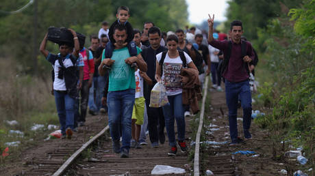 FILE PHOTO: Migrants and refugees celebrate as they cross the border from Serbia into Hungary along the railway tracks.