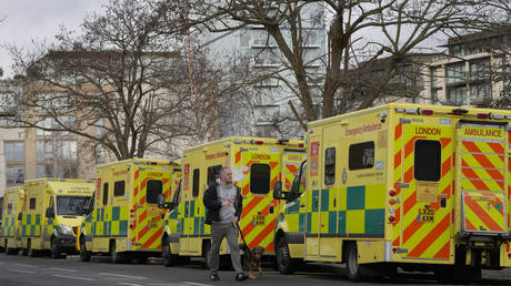 A man passes a line of parked ambulances in London, Britain, December 21, 2022