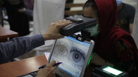 FILE PHOTO: An employee scans the eyes of a woman for biometric data at the passport office in Kabul, Afghanistan, June 30, 2021