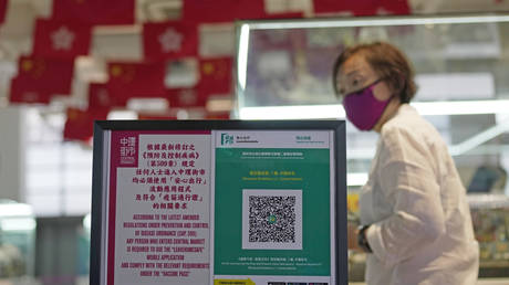 A woman walks past a government contact tracing QR code for the "LeaveHomeSafe" Covid-19 mobile app at a shopping mall in Hong Kong, July 12, 2022