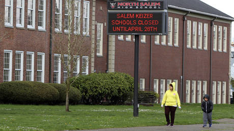 FILE PHOTO: A woman and child walk past North Salem High School in Salem, Oregon, March 31, 2020