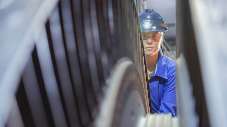 Female engineer inspecting a turbine in a nuclear power station in the UK.