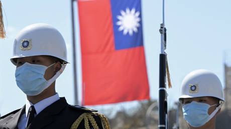 Taiwanese honour guards stand by under a national flag in front of the presidential office in Taipei on March 9, 2022.