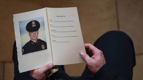 A US Capitol Police Officer holds a program as people pay their respects at the remains of US Capitol Police officer Brian Sicknick in Washington, DC, February 3, 2021