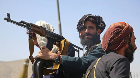 FILE PHOTO. Taliban fighters stand guard in a vehicle along the roadside in Kabul, Afghanistan.
