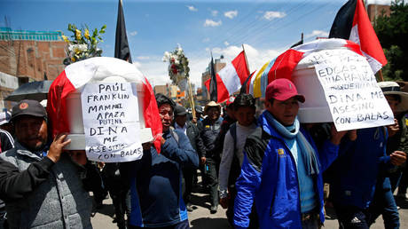Peruvians carry coffins with the message "Dina killed me with bullets" during a funeral procession in Juliaca, January 11, 2023.