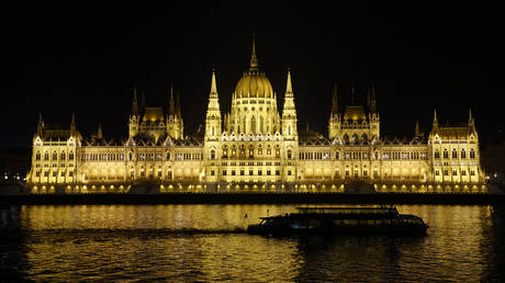 A boat passes on the Danube River in front of the Hungarian Parliament Building in Budapest on late December 13, 2021.