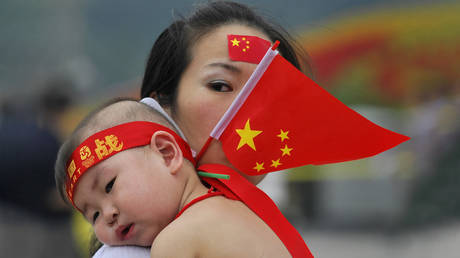 FILE PHOTO. A woman holding a Chinese flag carries a baby in Tiananmen square in Beijing, China.