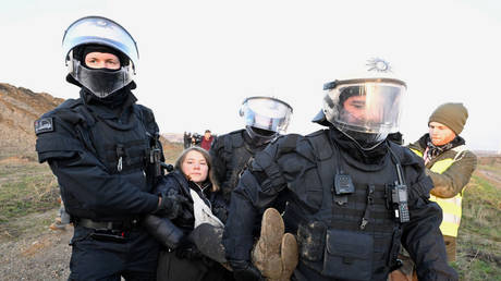 17 January 2023, North Rhine-Westphalia, Erkelenz: Police officers carry Swedish climate activist Greta Thunberg (M) out of a group of protesters and activists and away from the edge of the Garzweiler II opencast lignite mine.
