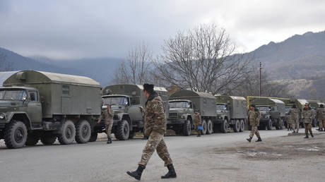 FILE PHOTO. Armenian servicemen walk next to a column of military trucks.