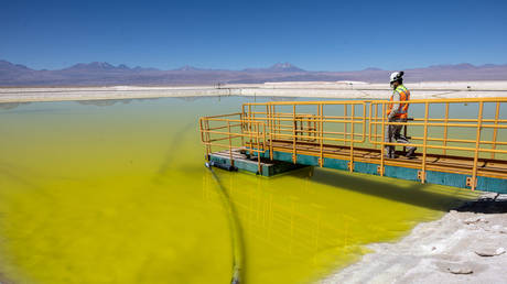 A lithium mine supervisor inspects an evaporation pond of lithium-rich brine in the Atacama Desert on August 24, 2022 in Salar de Atacama, Chile.