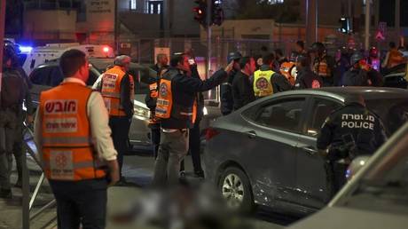 Emergency service personnel and security forces stand near a covered body at the site of a deadly terror shooting attack in the Jerusalem neighborhood of Neve Yaakov, on January 27, 2023