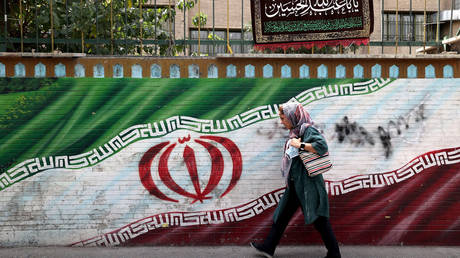An Iranian woman walks past a mural in the capital Tehran, on July 31 2022.
