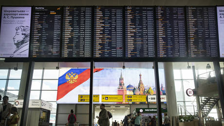 FILE PHOTO: Passengers walk past a departure board at Sheremetyevo international airport in Moscow, Russia, July 8, 2019