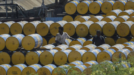 A worker stacks oil barrels at a filling station in n Chennai on February 24, 2022.