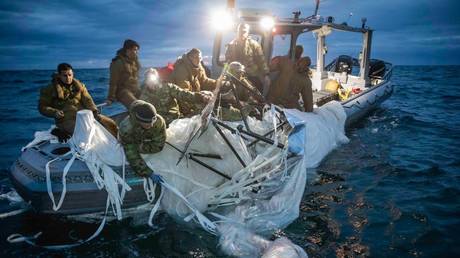 US Navy service members recover debris on Sunday from a high-altitude Chinese balloon that was shot down off the coast of South Carolina.