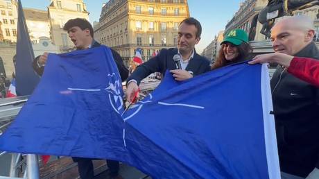 Les Patriotes party leader Florian Philippot cuts NATO’s flag during a rally in Paris.