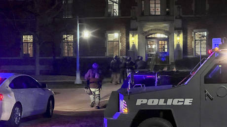 Armed police officers with weapons drawn rush into Phillips Hall on the campus of Michigan State University in East Lansing as authorities respond to reports of shootings, February 13, 2023