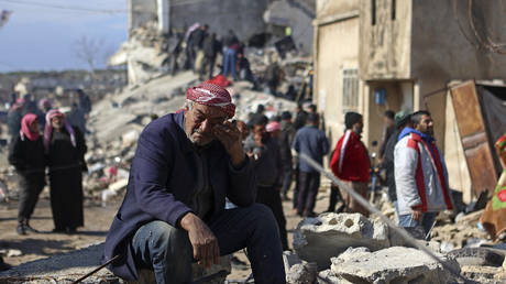 A Syrian man cries as he sits on the rubble of a collapsed building in the rebel-held town of Jindayris on February 7, 2023, following a deadly quake.