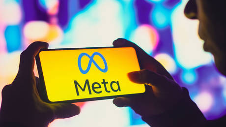 In this photo illustration, a silhouetted woman holds a smartphone with the Meta Platforms, Inc. logo displayed on the screen