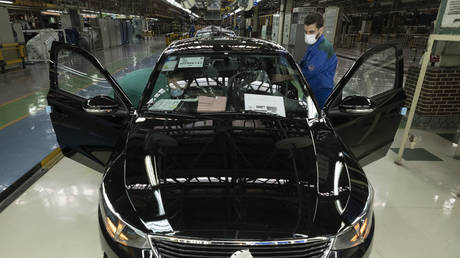 Two Iranian workers check an assembled vehicle at a production line of Iran Khodro Automaker Company (IKCO), 13 km (8 miles) west of Tehran on January 10, 2023.