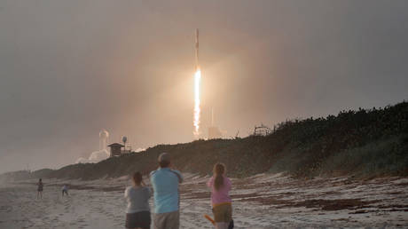 Spectators watch from Canaveral National Seashore as a SpaceX Falcon 9 rocket carrying 60 Starlink satellites launches at the Kennedy Space Center on October 6, 2020