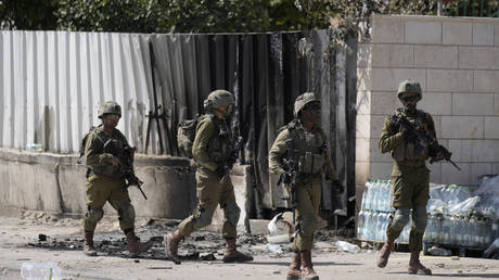 Israeli soldiers patrol an area damaged by fires from torched vehicles during a rampage by settlers in Hawara, West Bank, March 1, 2023