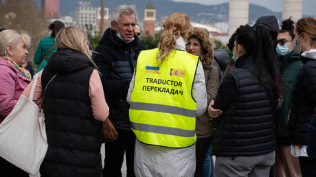 FILE PHOTO. A translator speaks with Ukrainian refugees outside a newly-opened reception centre set up at the municipal pavilion of the Fira in Barcelona, on March 18, 2022.