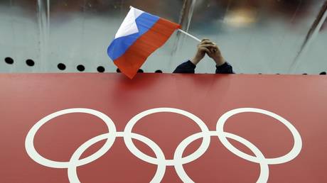 FILE PHOTO: A Russian flag is held above the Olympic Rings at Adler Arena Skating Center during the Winter Olympics in Sochi, Russia, February 18, 2014