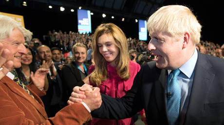 Boris Johnson greets his father Stanley Johnson as he exits the hall with his girlfriend Carrie Symonds following his keynote speech on day four of the 2019 Conservative Party Conference at Manchester Central on October 2, 2019