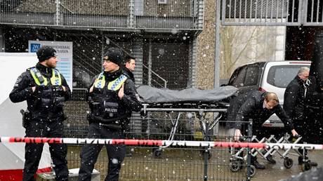 Police stand behind a cordon as the body of a victim is taken away after a shooting in Hamburg, Germany, March 10, 2023