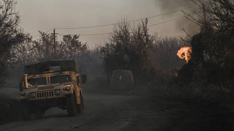 A Ukrainian military vehicle drives next to a burning land at the village of Chasov Yar near Artyomovsk.