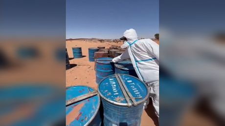 A worker is seen near barrels said to contain uranium ore concentrate at an undisclosed location in Libya, March 16, 2023.