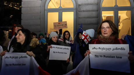 Protesters hold placards during a rally against the Georgian government and the adoption of the Russian law on foreign agents, near the European Parliament headquarters in Brussels on March 8, 2023.