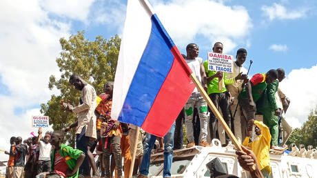 FILE PHOTO: Protesters stand atop a Unitend Nation armored vehicle as they demonstrate carrying a Russian flag in Ouagadougou on October 2, 2022.