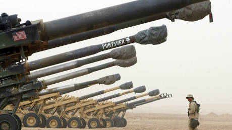 FILE PHOTO: A US Marine of the 1st Marine Division walks past 155 mm howitzers that are lined up February 20, 2003 near the Iraqi border in Kuwait.