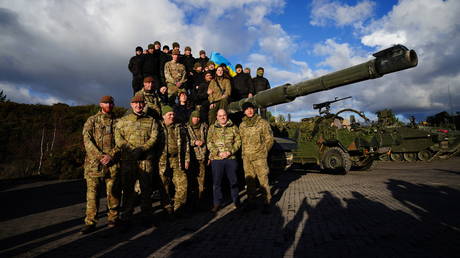 Britain's Defence Secretary Ben Wallace poses in front of a Challenger 2 tank with Ukrainian soldiers undergoing training in UK.