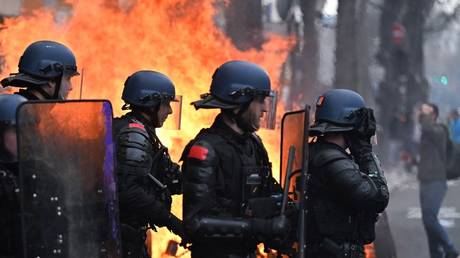 Riot police officers walk by a fire during a rally in Paris.