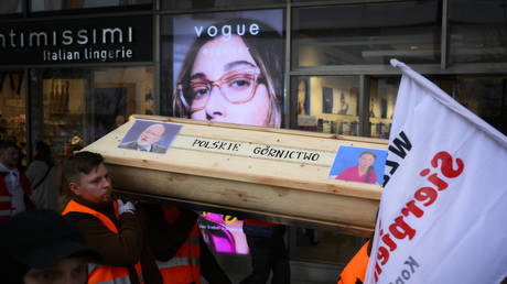 Miners carry a wooden coffin with an images of Frans Timmermans and Greta Thunberg during a protest in Warsaw, Poland on 24 March, 2023