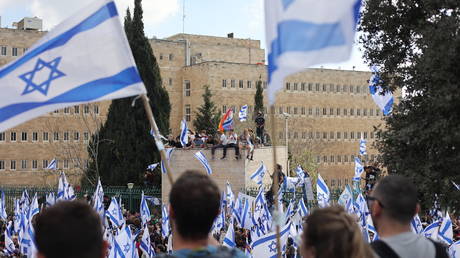 Demonstrators hold Israeli flags during a protest against juridical reform in Jerusalem on March 27, 2023.