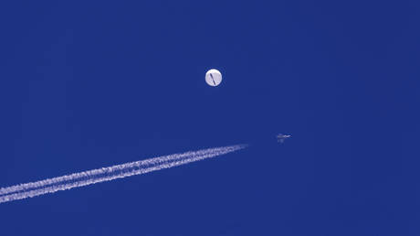 FILE PHOTO: A fighter jet flies near a large balloon drifting above the Atlantic Ocean, just off the coast of South Carolina, February 4, 2023