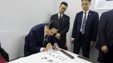 Former Taiwanese President Ma Ying-jeou (center) writes calligraphy on Tuesday at the Sun Yat-sen mausoleum in Nanjing, China.