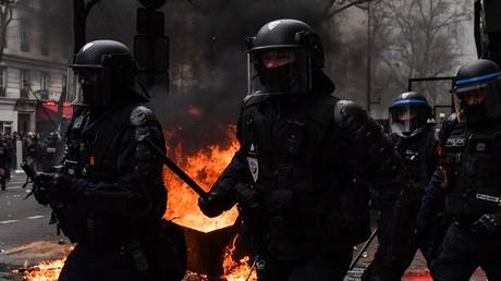 Riot police charge past burning garbage bins in the street during a demonstration in Paris, France, March 28, 2023
