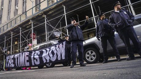 Demonstrators unveil a banner outside Manhattan's district attorney office in New York, March 30, 2023