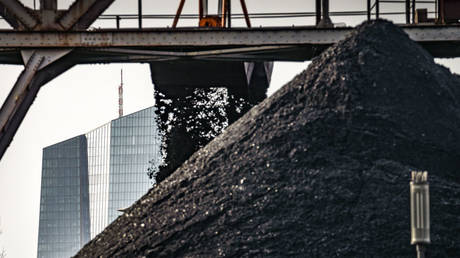 An excavator unloads coal from a barge onto a stockpile next to a power plant, while the European Central Bank (ECB) headquarters can be seen in the background (l), 03 January 2022, Hessen, Offenbach