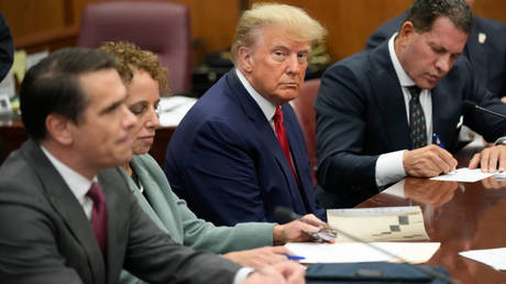 Former US President Donald Trump sits in a New York City courtroom, flanked by his lawyers, as he's arraigned on Tuesday on 34 criminal counts.